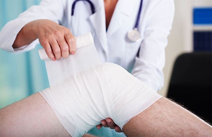 doctor bandând articulația genunchiului cu artroză